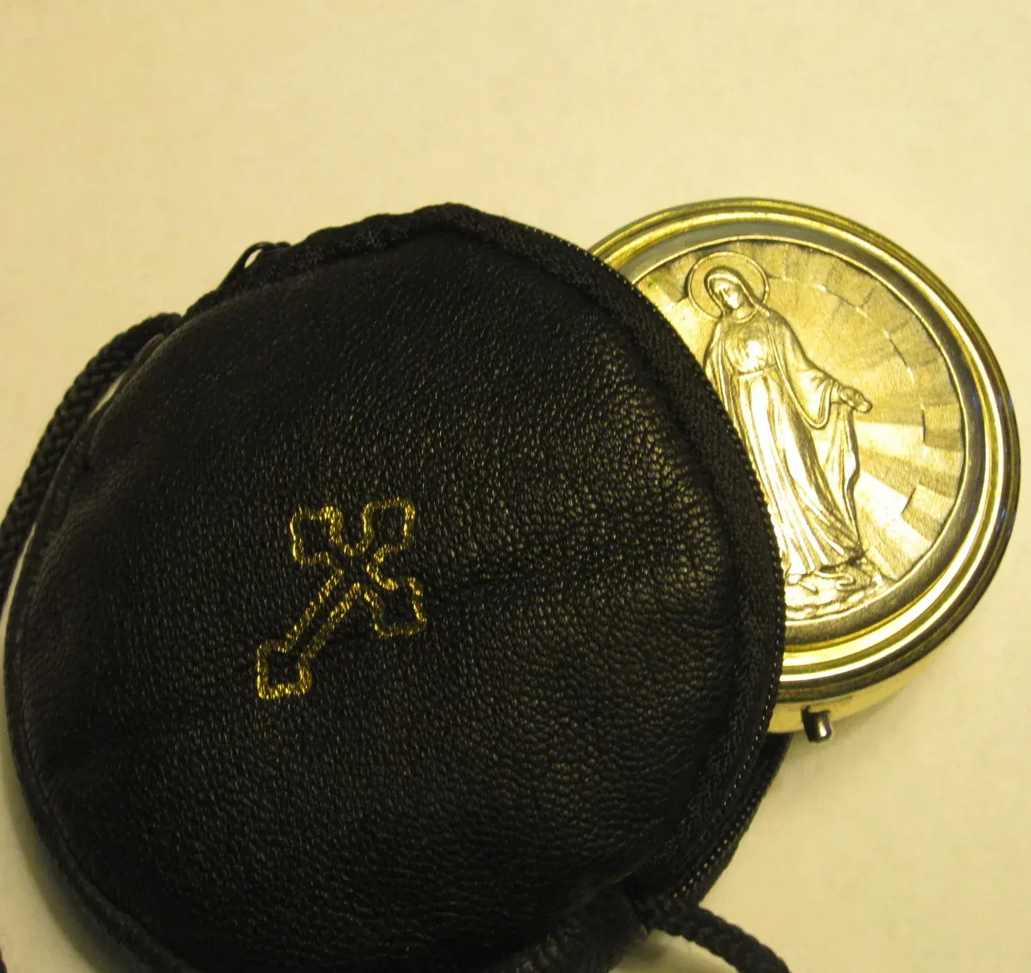 Black leather coin purse with gold emblem, partly open to show a gold coin inside.