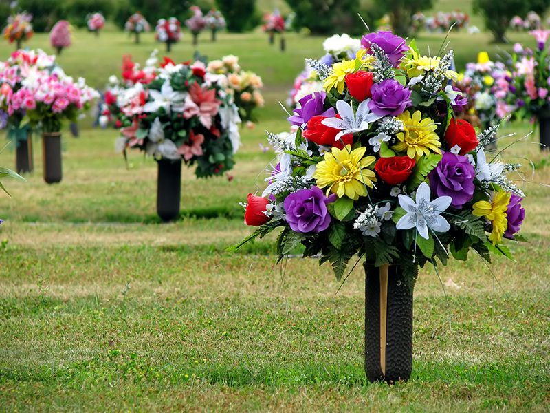a urn surrounded by yellow roses and leaves on a table .