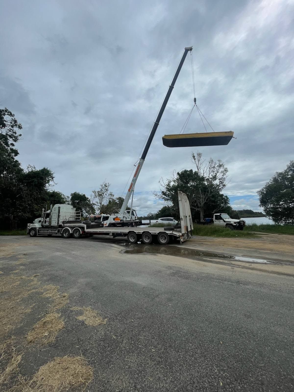 Crane Loading a Long Steel Beam onto A Truck on A Roadside — Rainbow and Sons Heavy Haulage in Wells Crossing, NSW