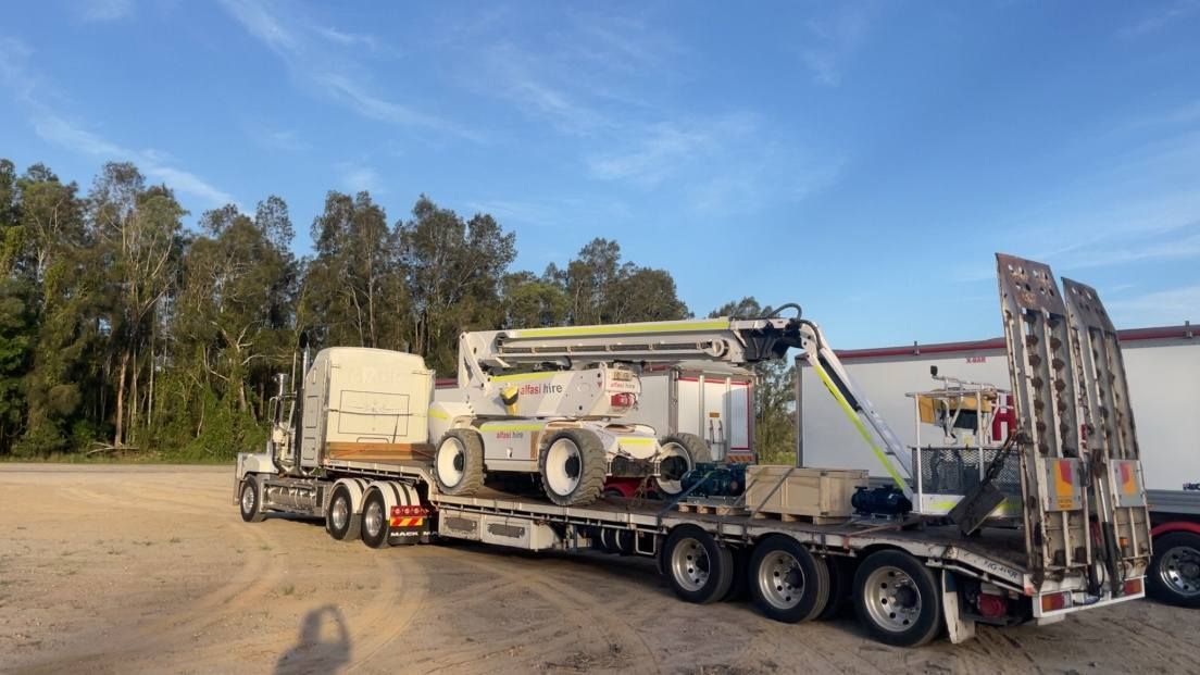 Heavy Equipment on A Flatbed Trailer Parked on A Dirt Lot — Rainbow and Sons Heavy Haulage in Wells Crossing, NSW