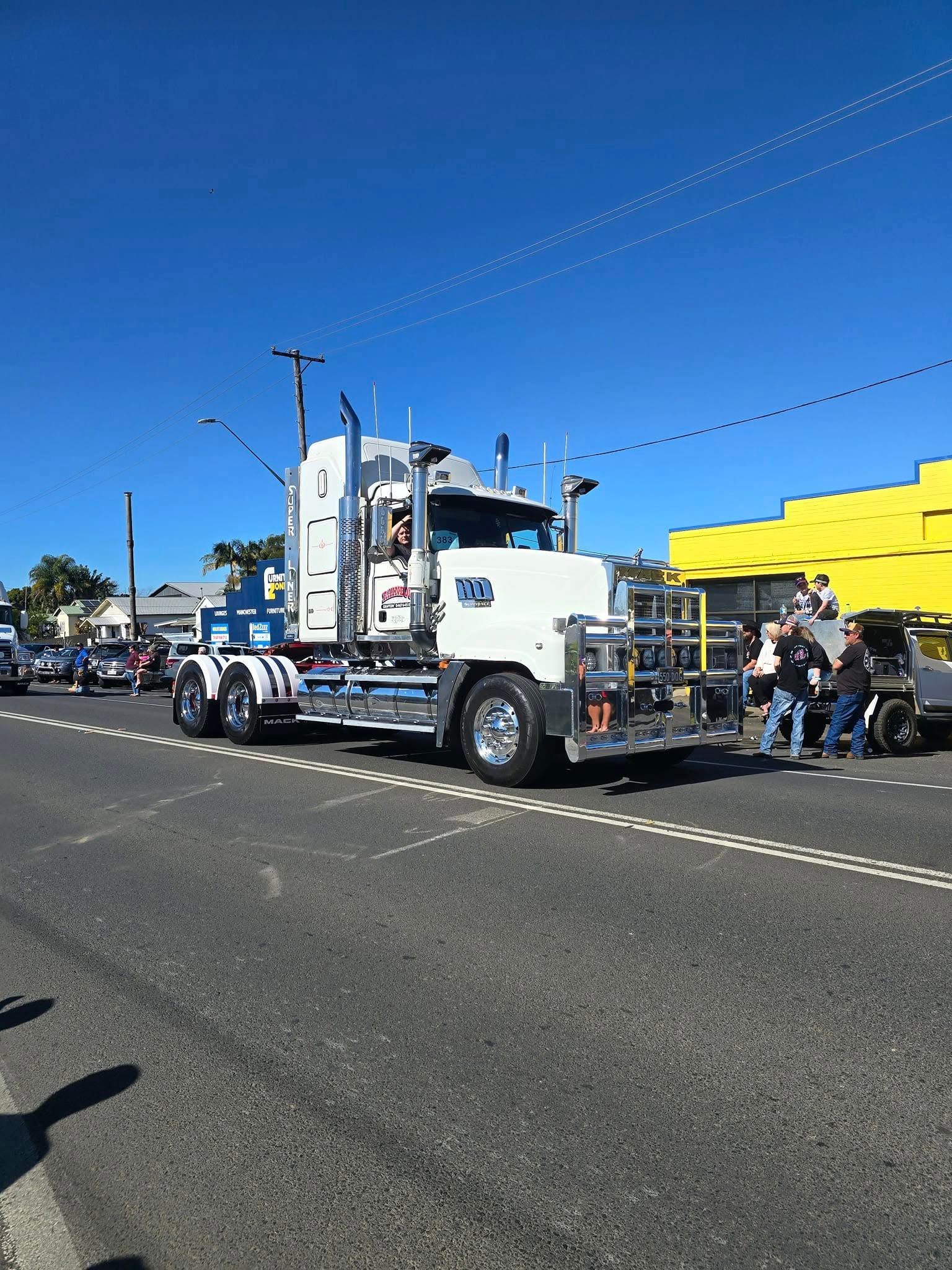 Tow Truck Parked on A Sunny Street Beside Yellow Buildings — Rainbow and Sons Heavy Haulage in Coffs Harbour, NSW