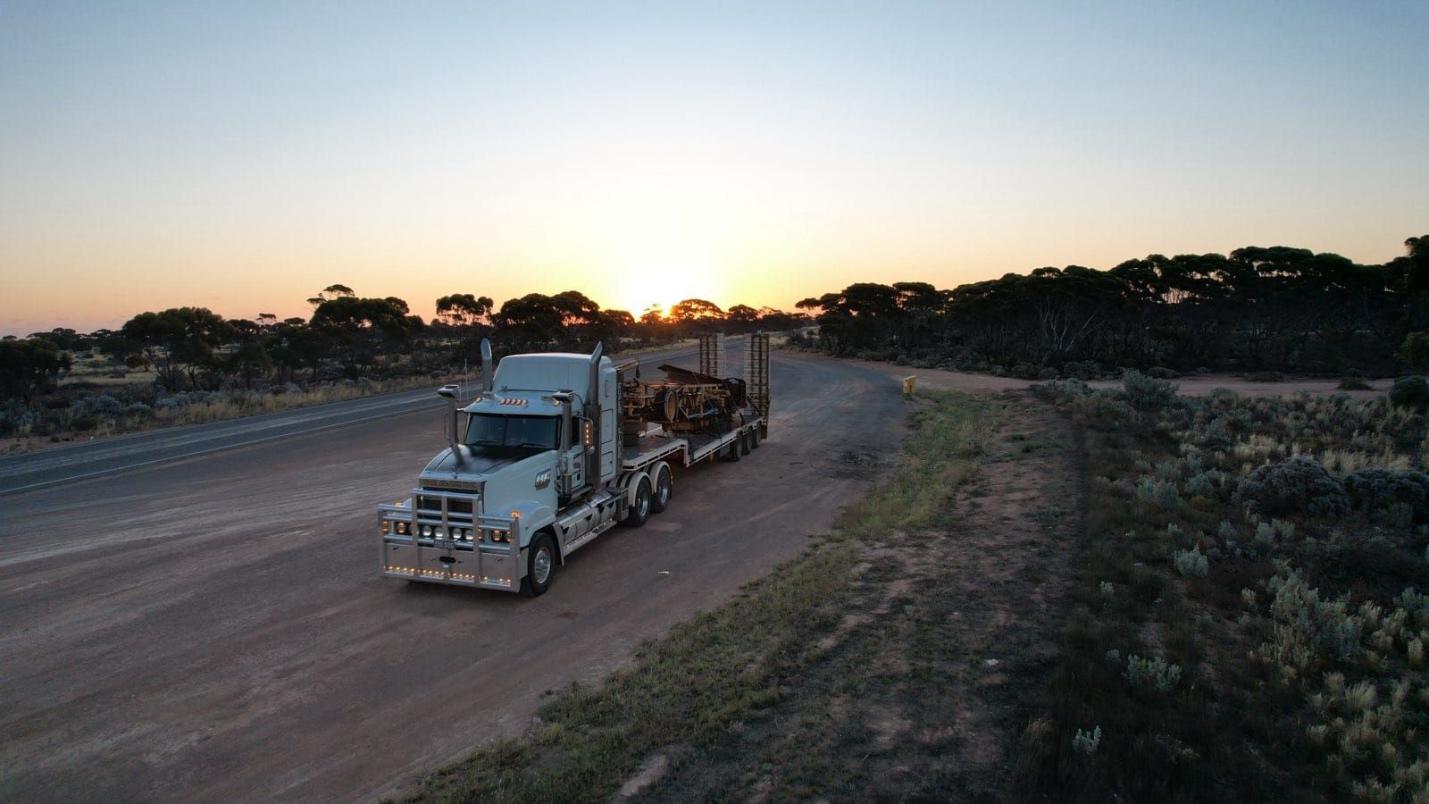 Semi-Truck Hauling Timber on A Dirt Road at Sunset — Rainbow and Sons Heavy Haulage in Coffs Harbour, NSW