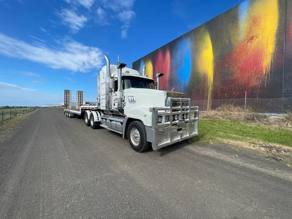 White Semi-Truck on A Gravel Road Beside a Large Wall Mural — Rainbow and Sons Heavy Haulage in Wells Crossing, NSW