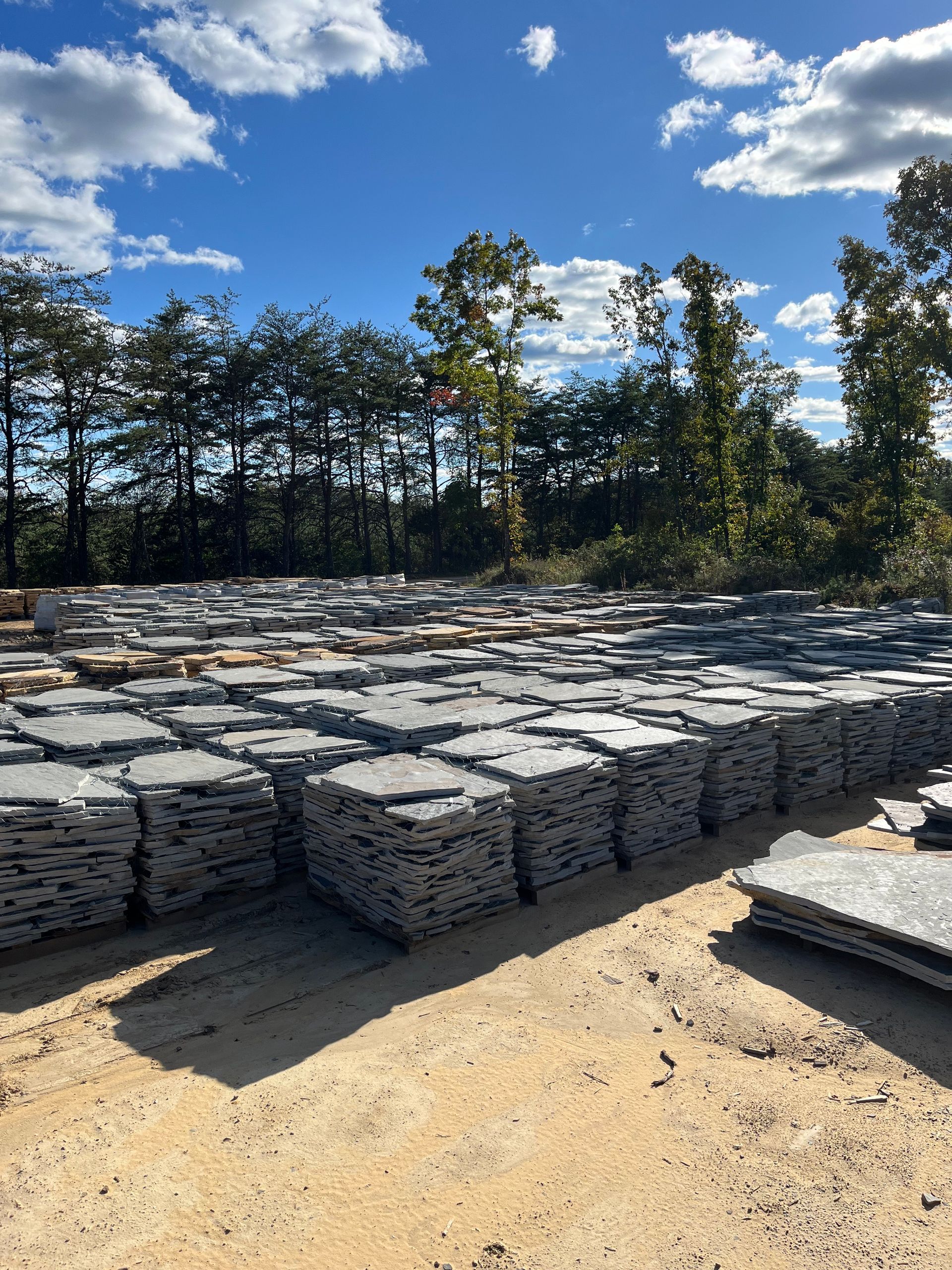 A large pile of rocks in a field with trees in the background