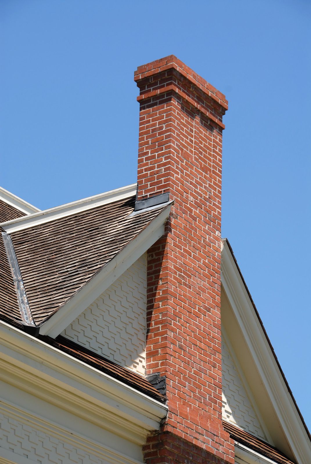 Brick chimney on a house roof against a blue sky