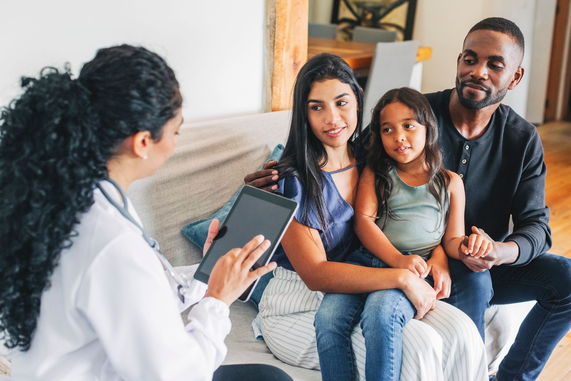 A doctor is talking to a family sitting on a couch.