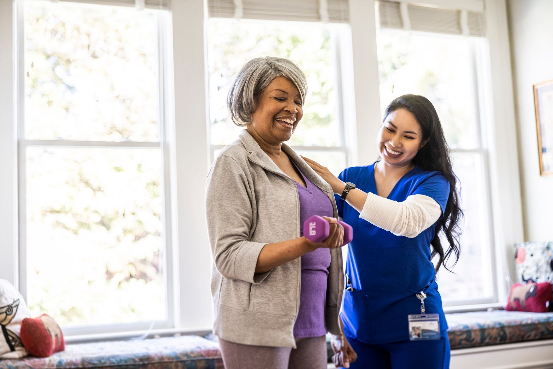 A nurse is helping an elderly woman exercise with dumbbells.