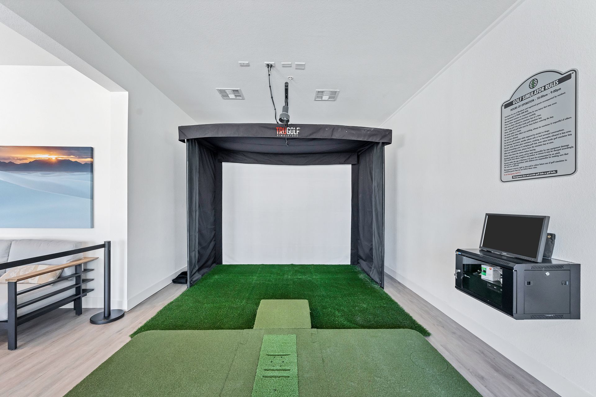 Indoor golf simulator room with putting green, hitting net, and wall-mounted screens