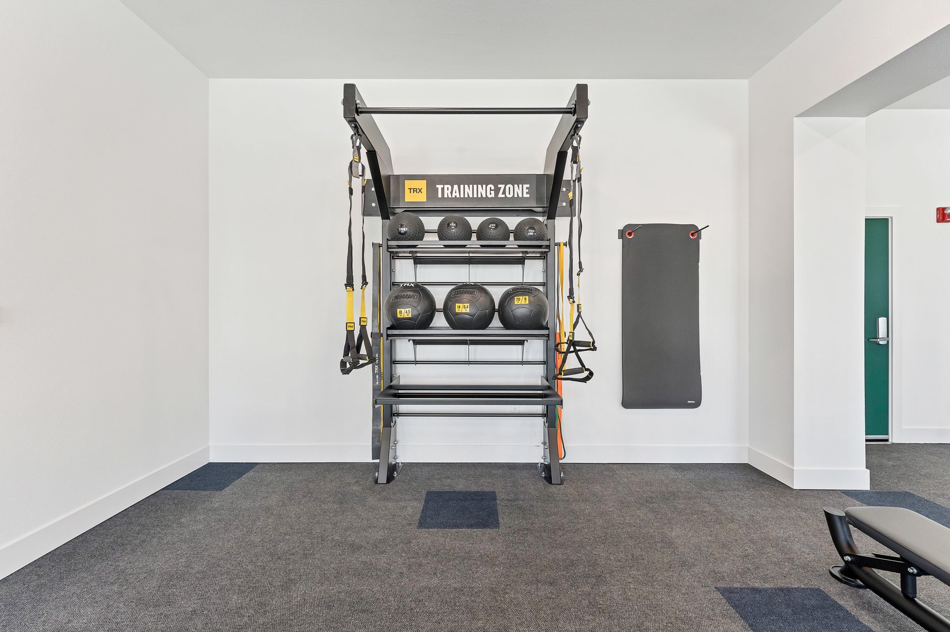Home gym with a workout rack, dumbbells, and a punching bag against a white wall