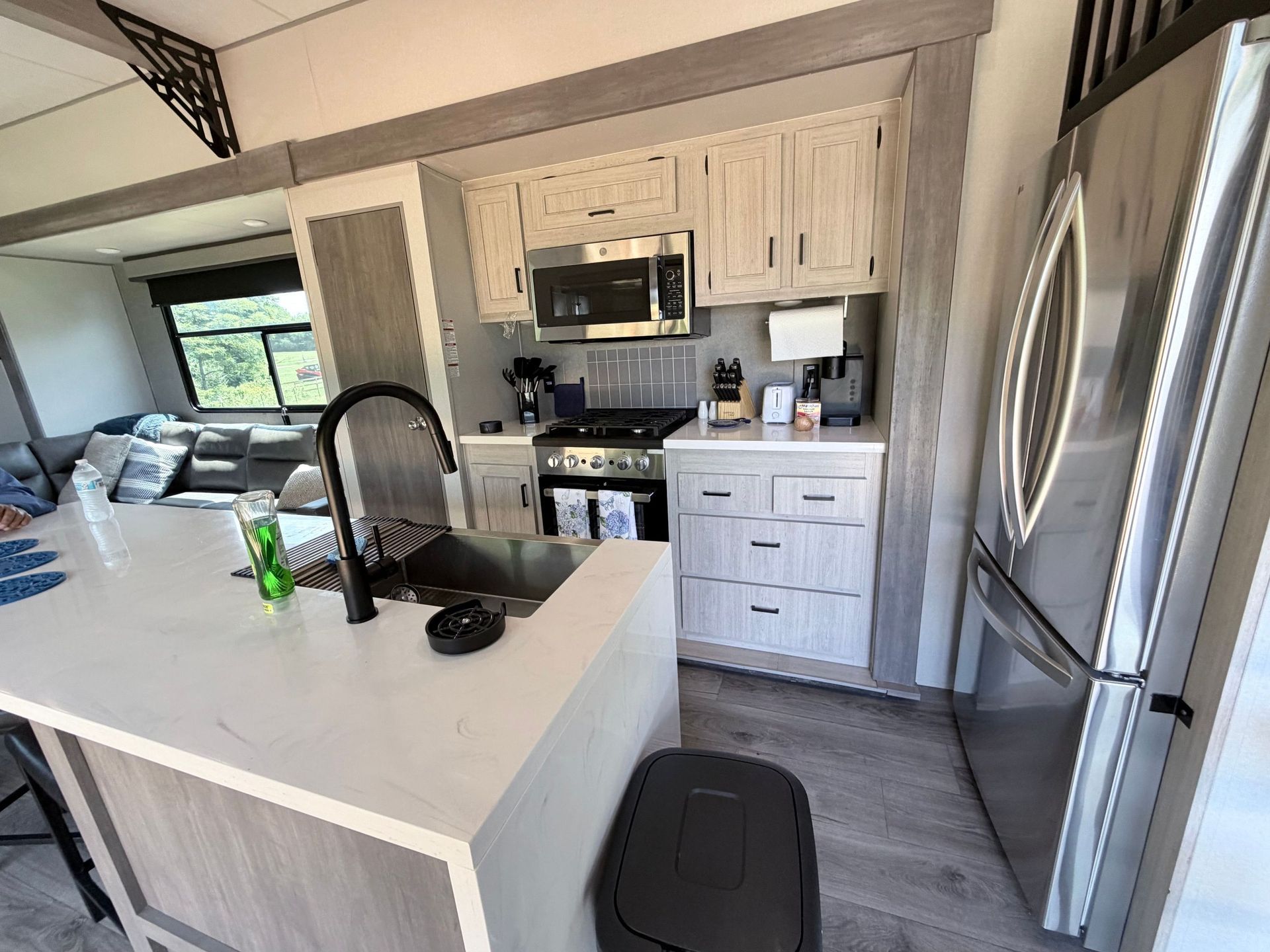 Modern kitchen with white island, black faucet, stainless appliances, and gray flooring