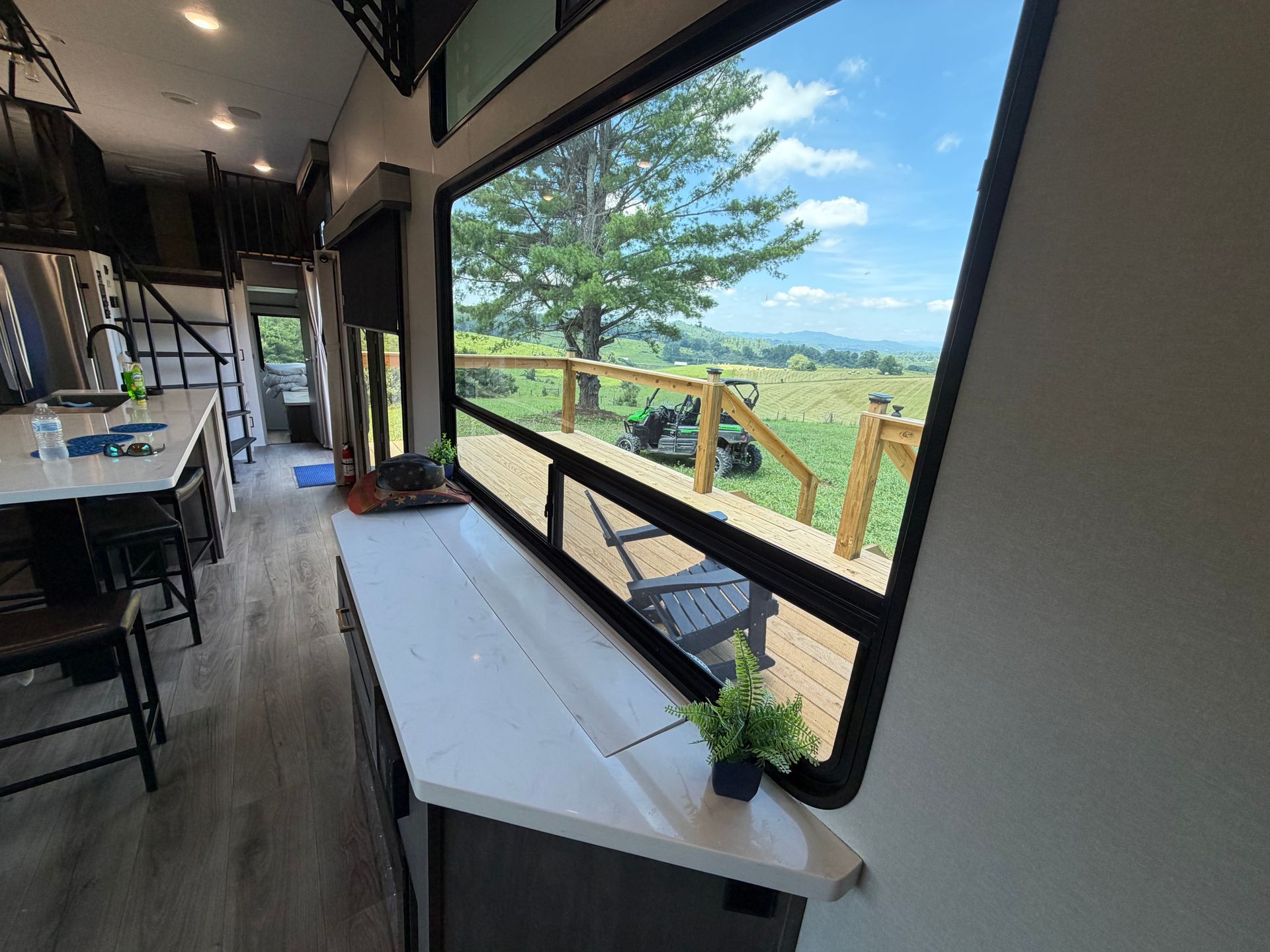 Covered porch with long white table, chairs, and open view of green fields and blue sky