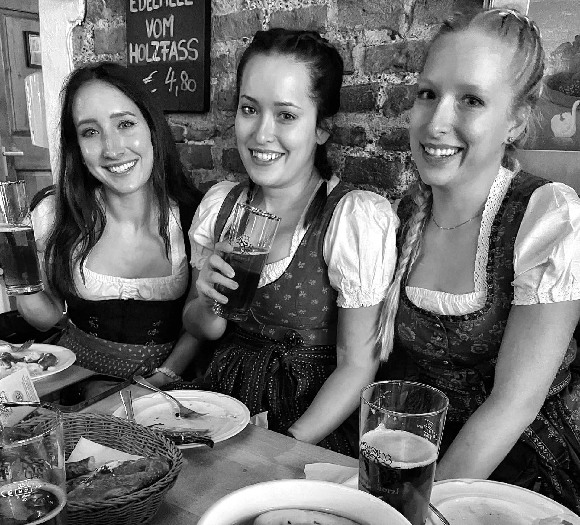 Three women are sitting at a table with plates of food and drinks.