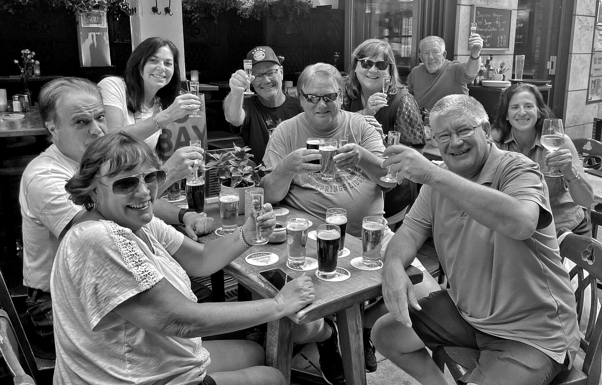 A group of people are sitting at a table toasting with beer glasses.