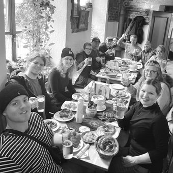A group of people are sitting at a table with plates of food and drinks.