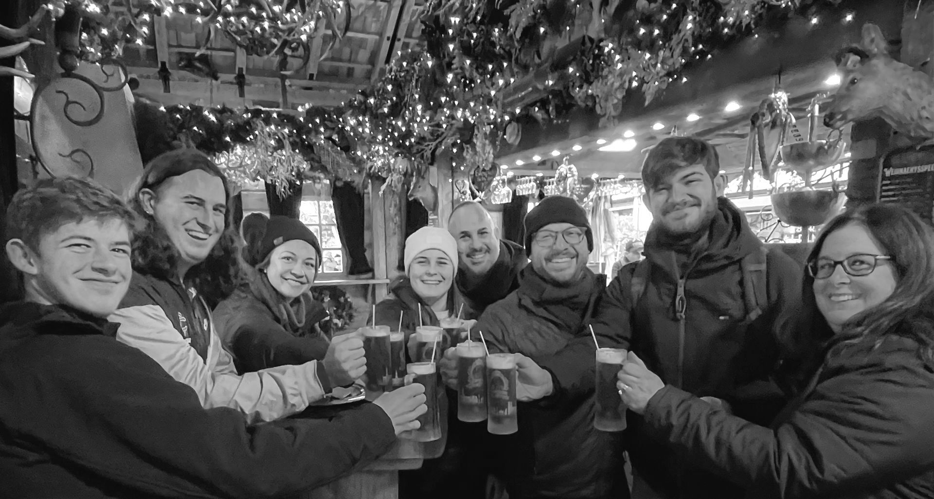 A group of people are toasting with beer in a black and white photo.