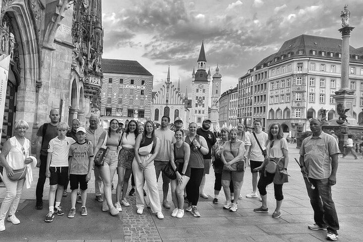 A group of people are standing in front of a building in a black and white photo.