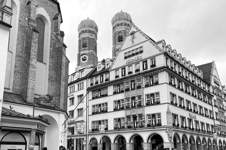 A black and white photo of a building with a church in the background.