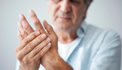 An older man is holding his hand in pain.