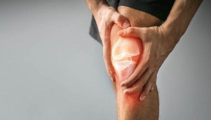 A man is holding his knee in pain.
