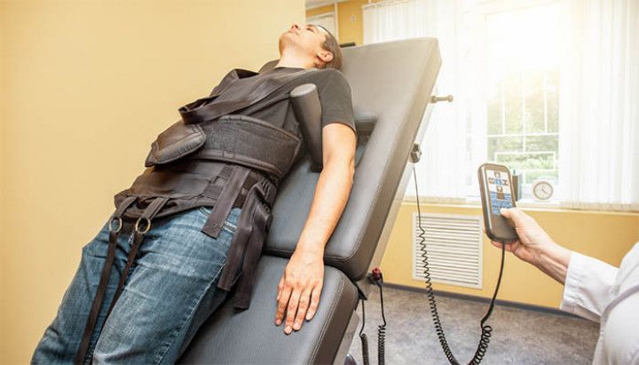 A man is laying on a table with a device on his back.