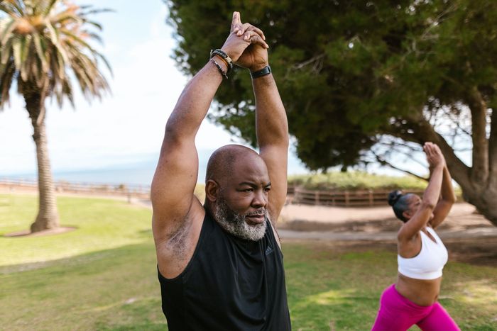 A man and a woman are doing yoga in a park.