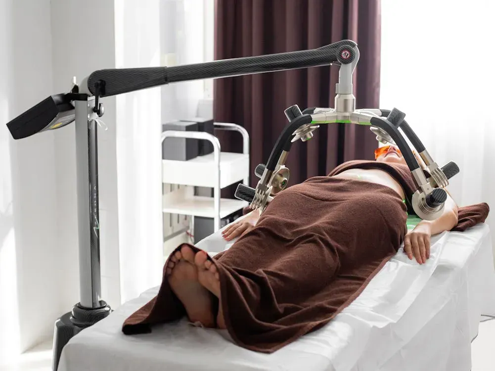 A woman is laying on a bed with a machine on her stomach.
