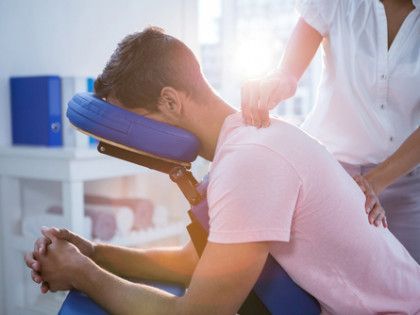 A man is sitting in a chair getting a massage from a woman.