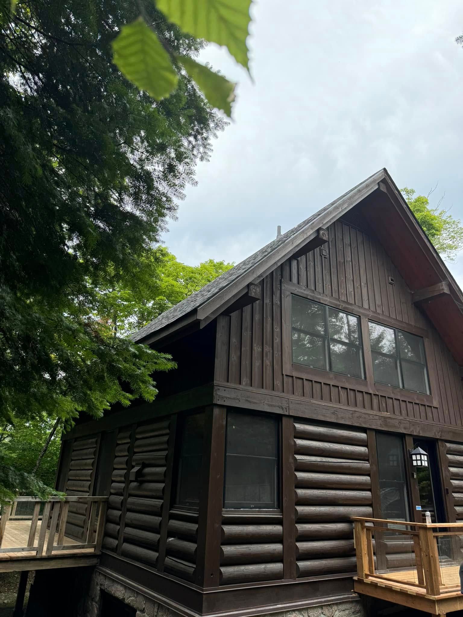 Une cabane en rondins avec une terrasse et des arbres en arrière-plan.