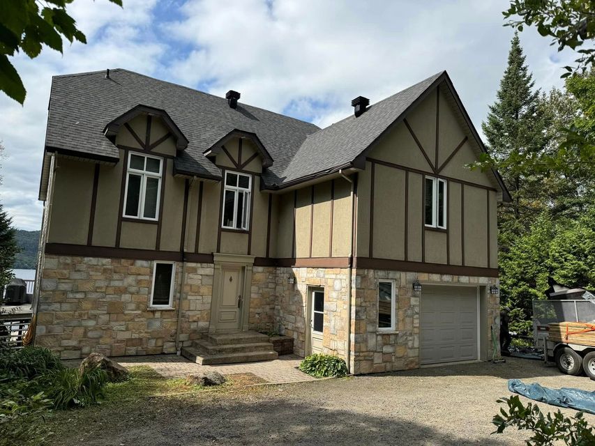 Une grande maison en pierre avec un toit gris et un garage.