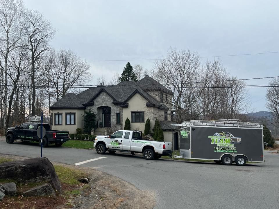 Deux camions sont garés sur le bord de la route devant une maison.