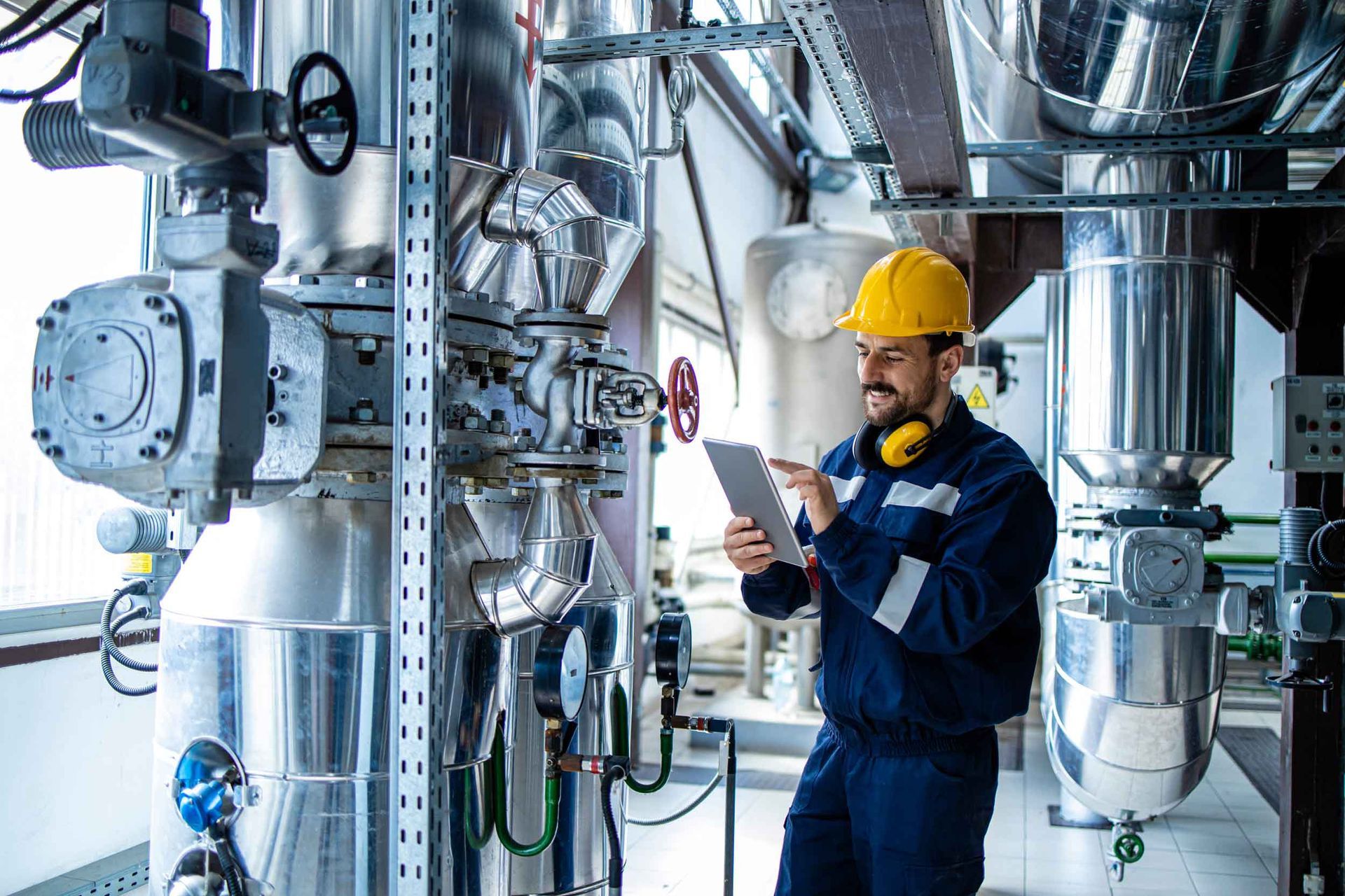 Heating plant interior with pipes and valves and a factory worker controlling the process of boiling. Heating plant interior with pipes and valves and a factory worker controlling the process of boiling.