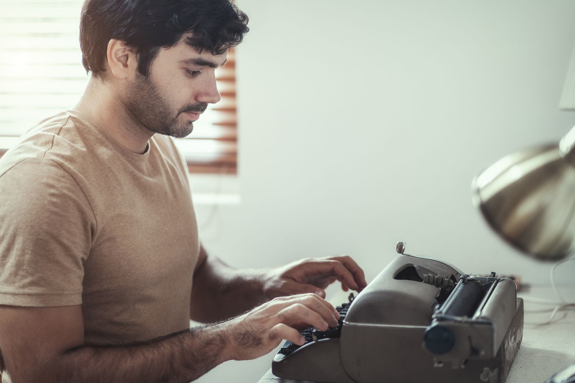 A man types on a retro typewriter in his office. A man types on a retro typewriter in his office.