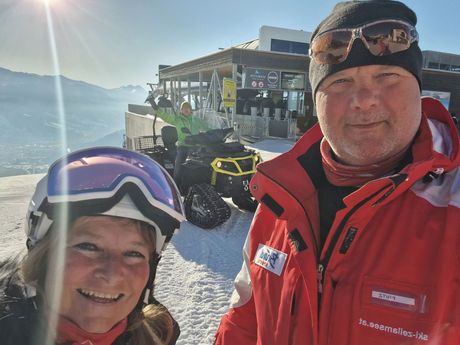 Fritz en Jolanda op de piste, met de sneeuwscooter op de achtergrond