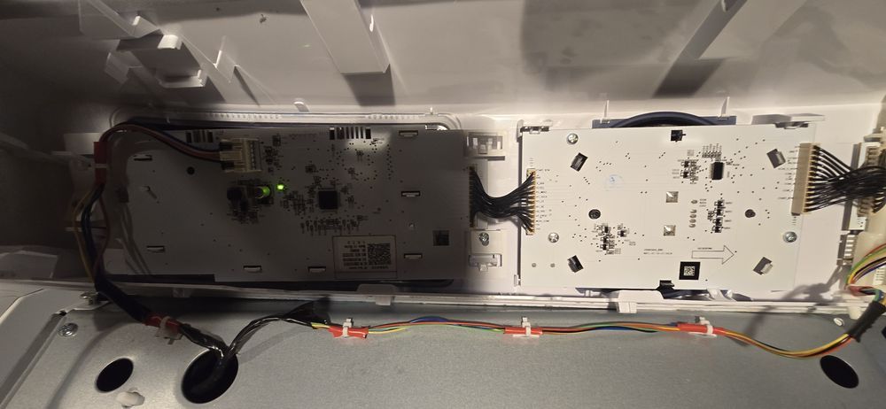 The inside of a refrigerator with a lot of wires coming out of it.