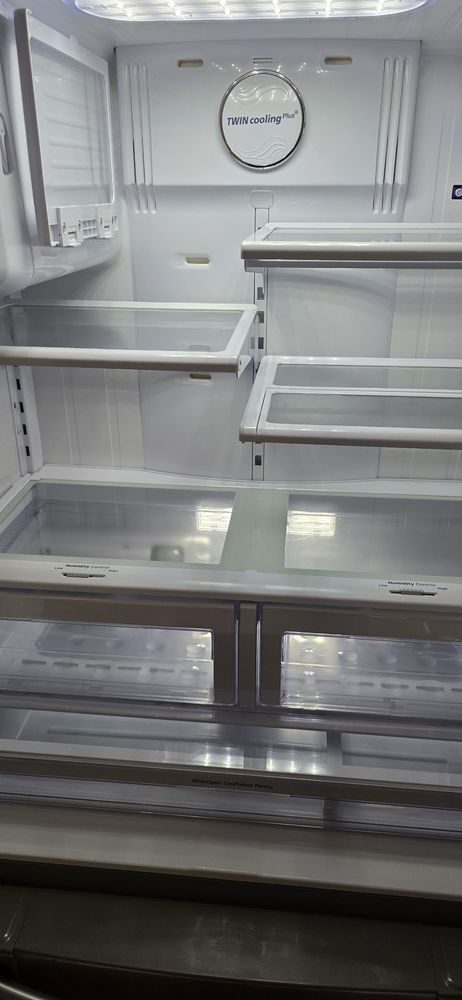 The inside of an empty refrigerator with a clock on the wall.