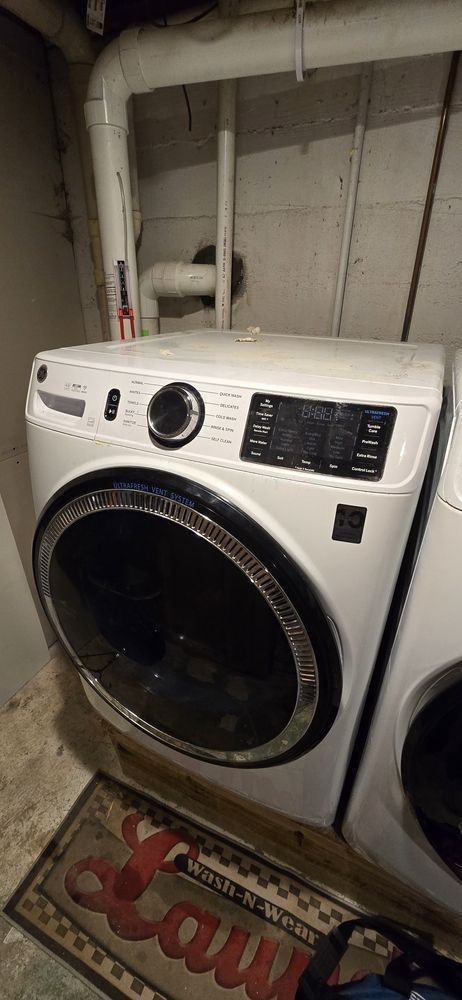 A white washing machine and dryer are sitting next to each other in a laundry room.