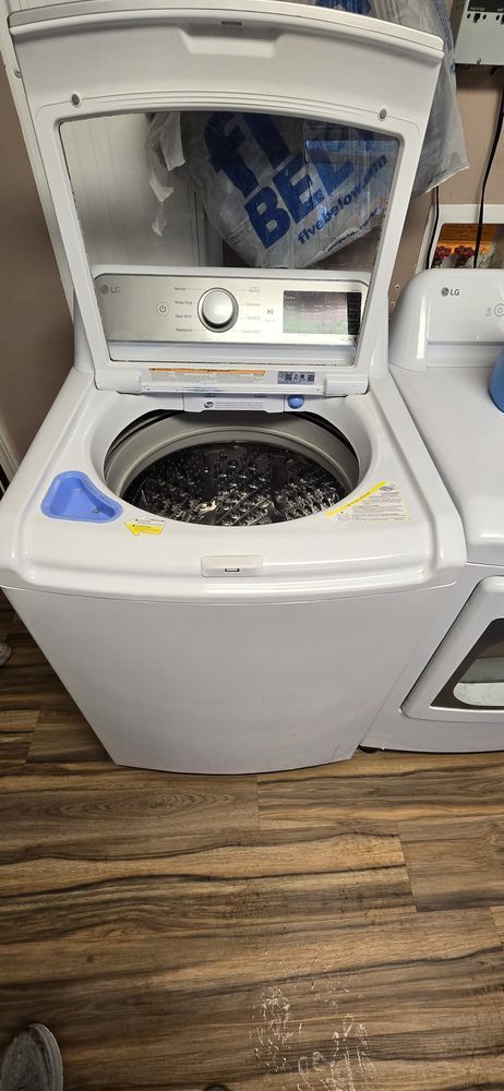 A white washer and dryer are sitting on a wooden floor.