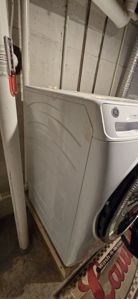 A white washer and dryer are sitting in a basement.