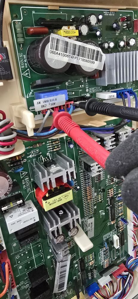 A person is using a multimeter to test a motherboard.