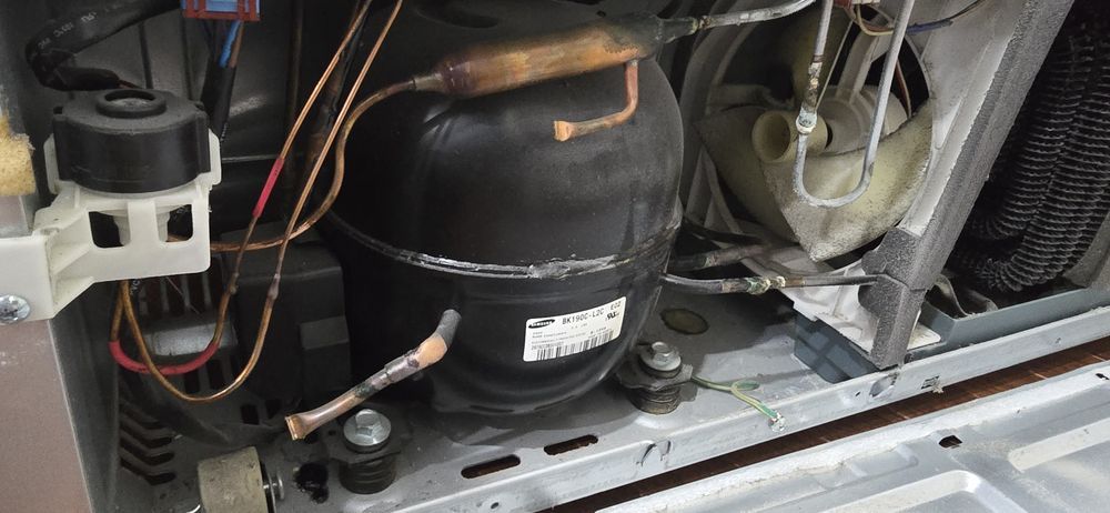 The inside of a refrigerator with a compressor and a fan.