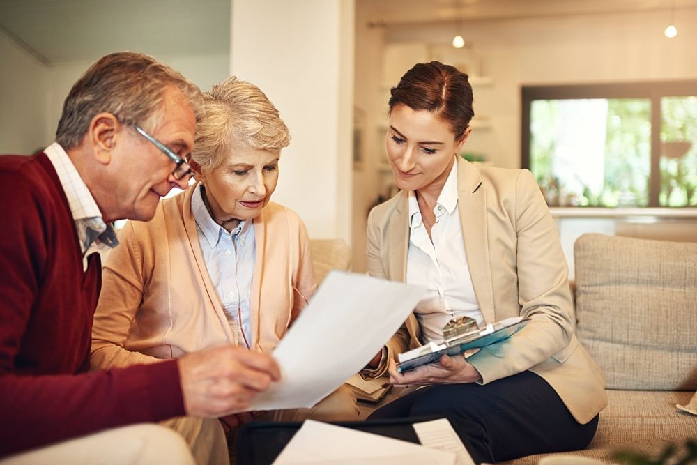 Senior couple reviewing documents with a financial advisor in their home.