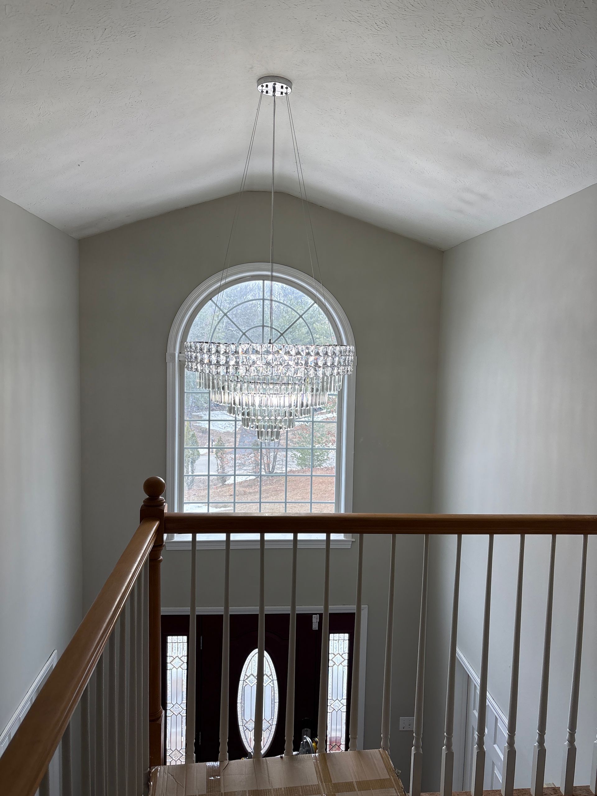 Stair landing with white railing and arched window overlooking snowy trees outside