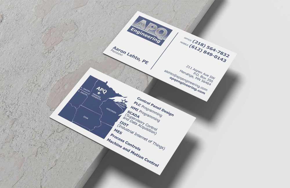 Two white business cards with dark blue text and a logo for APQ Engineering, resting on a concrete surface.