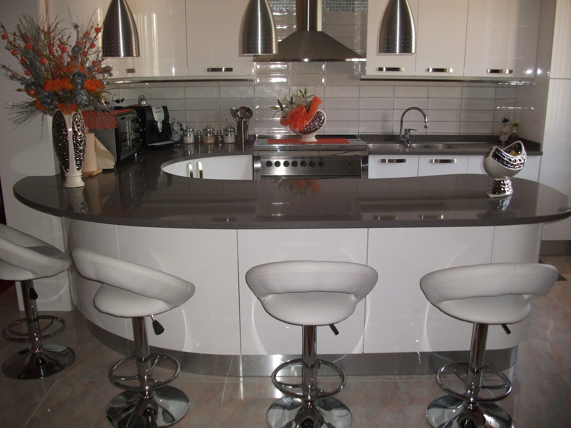 Una cucina con mobili e sgabelli bianchi e una grande isola