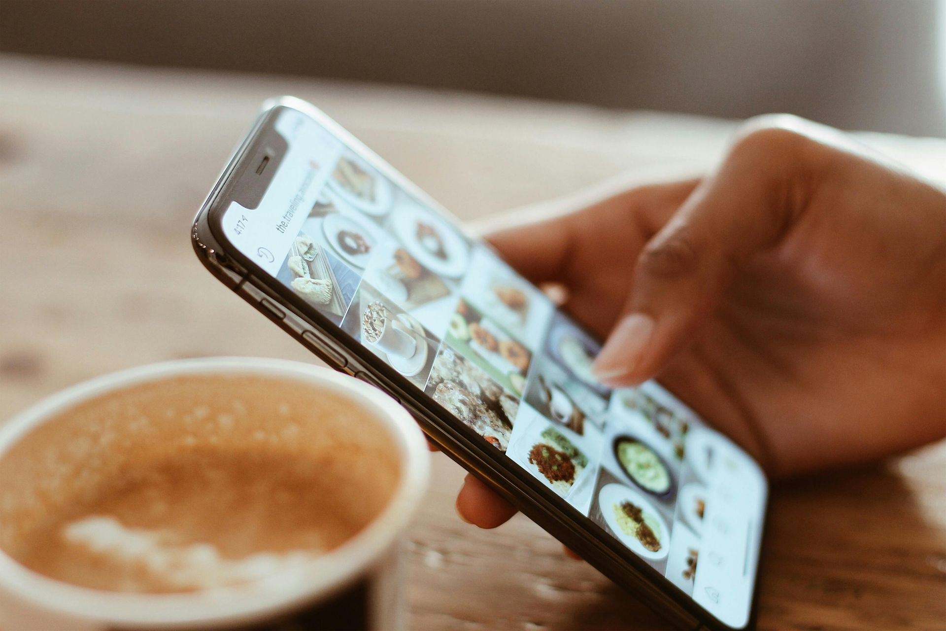Side view of a hand holding a smartphone with Instagram/Threads feed scrolling in the background, symbolizing active social media engagement and connectivity