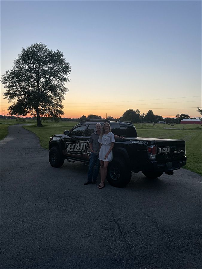 A man and a woman are standing in front of a truck.