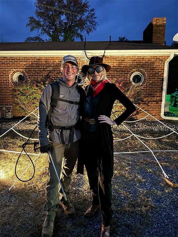 A man and a woman are posing for a picture in front of a brick house.
