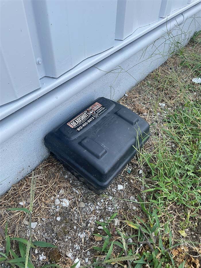 A mouse trap is sitting on the ground next to a building.