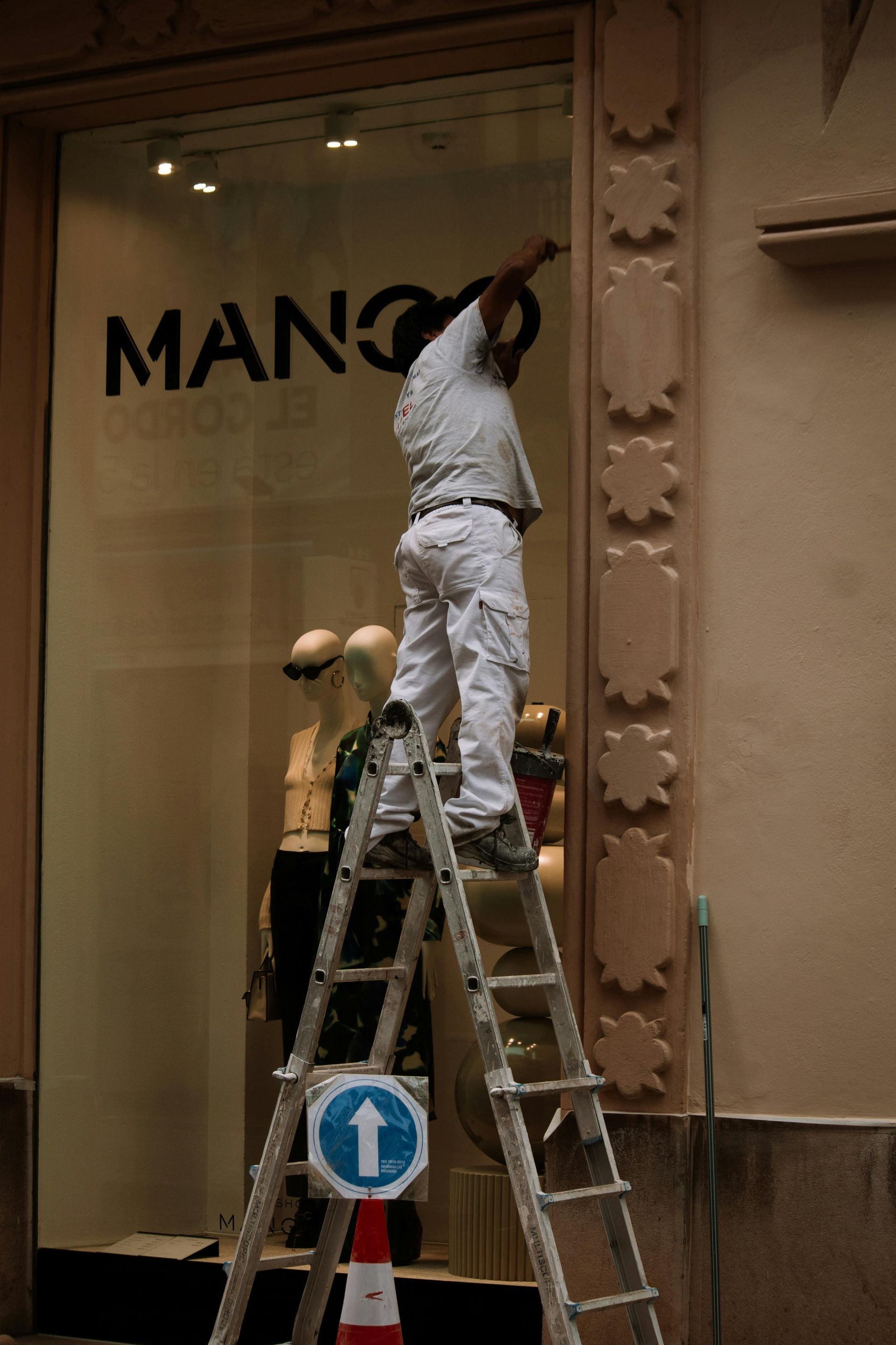 Person on ladder working on Mango store sign.