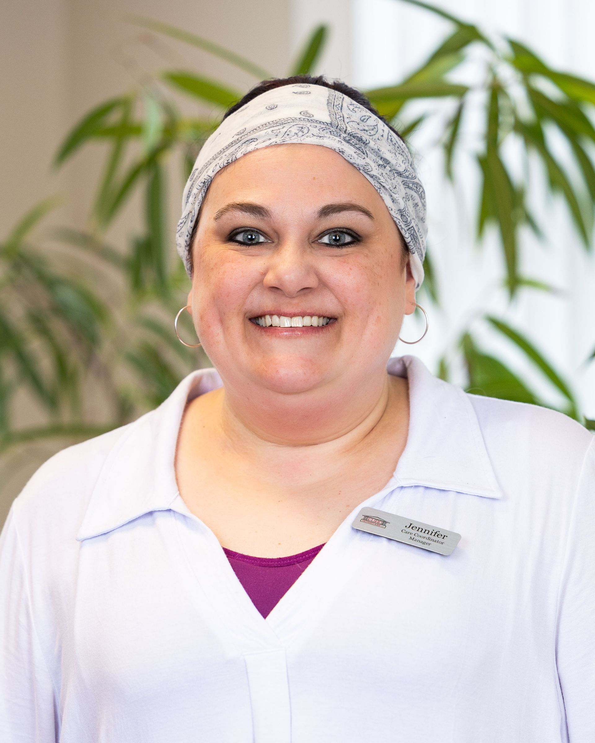 A woman wearing a headband and a white shirt is smiling for the camera.